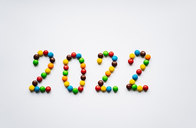 Année 2022 à partir de bonbons multicolores ronds sur fond blanc. photo de haute qualité