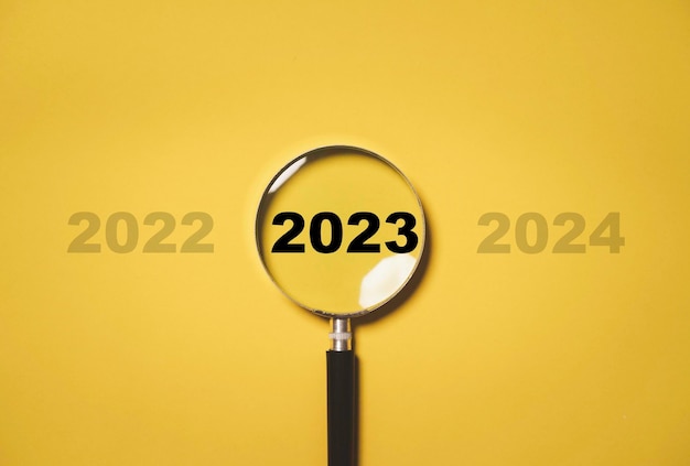 Année 2023 à l'intérieur de la loupe entre 2022 et 2023 pour se concentrer et se concentrer sur le concept de la nouvelle année commerciale Joyeux Noël et bonne année