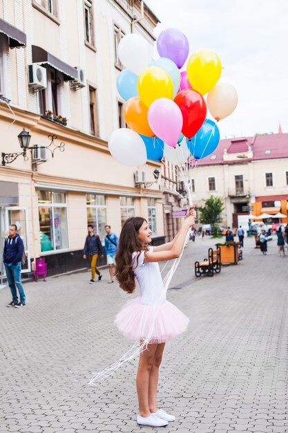 Anniversaire d'adolescent. Jolie fille avec de gros ballons colorés dans la rue d'une vieille ville