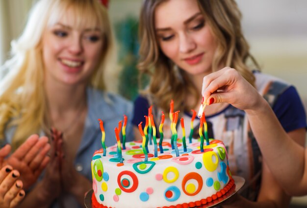 Photo anniversaire. les filles allument des bougies sur le gâteau.