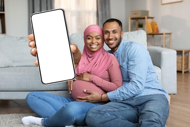 Annonce Mobile Joyeux Couple Musulman Noir Attend Bébé Montrant Grand Smartphone Vierge