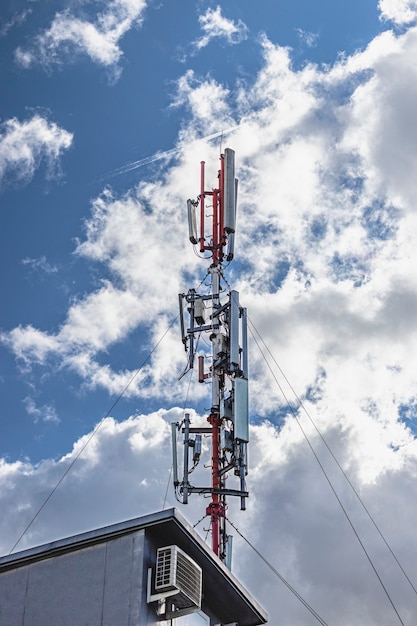 Antenne cellulaire contre un ciel bleu nuageux dans un quartier résidentiel résidentiel. Technologies de communication modernes.