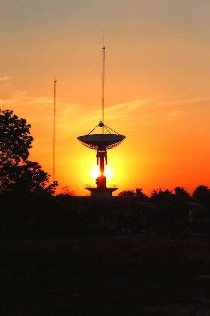 Photo une antenne satellite sur le terrain contre le ciel au coucher du soleil