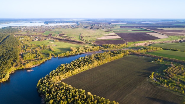 Antenne: survolant un champ dans les terres agricoles avec le soleil éclairant le champ. Tir de drone.