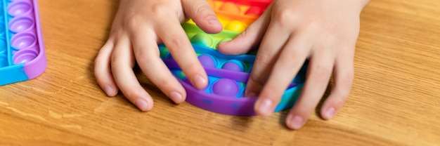 anti stress sensoriel pop it jouets dans les mains d'un enfant un petit garçon heureux joue avec un jouet