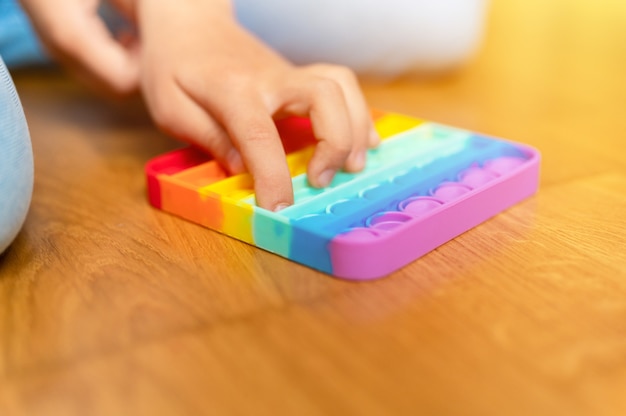 anti stress sensoriel pop it jouets dans les mains d'un enfant une petite fille heureuse joue avec un jouet