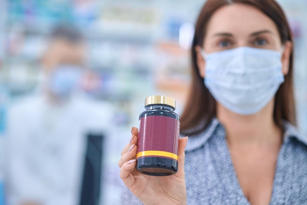 Anti-virus. Une femme dans un masque de protection tenant un pot avec des pilules