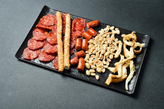 Photo antipasto appétit pour la bière le salami le fromage les noix et les saucisses sur un fond sombre en gros plan