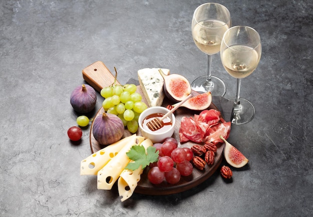 Antipasto avec prosciutto, fromage, figues et raisins, apéritif et vin blanc