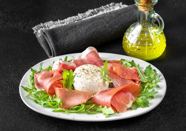 Antipasto avec prosciutto , mozzarella et roquette fraîche sur l'assiette de service