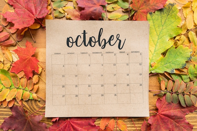 Aperçu de la feuille de calendrier d'octobre et groupe de feuilles d'automne colorées sur table en bois