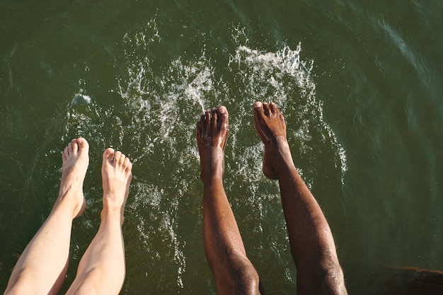 Aperçu des jambes du jeune couple interculturel aux projections d'eau