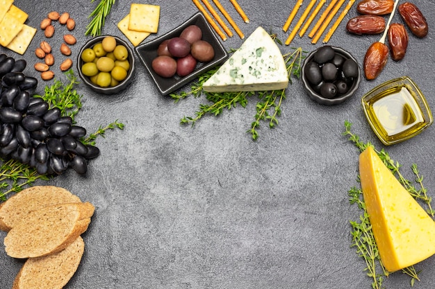 Apéritif d'apéritif avec olives et fromage raisins et dattes baguette et craquelins noix et brins de thym