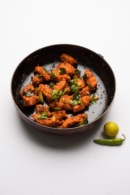 Apéritif de bar frit épicé 65 poulet ou collation rapide de l'Inde dans un bol ou une assiette sur fond blanc