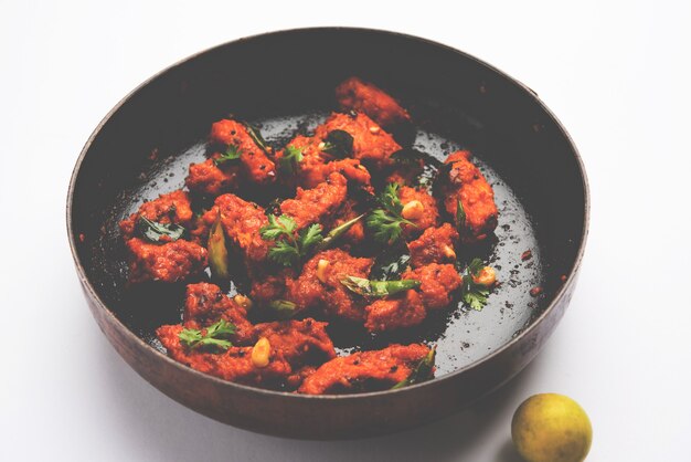 Apéritif de bar frit épicé 65 poulet ou collation rapide de l'Inde dans un bol ou une assiette sur fond blanc