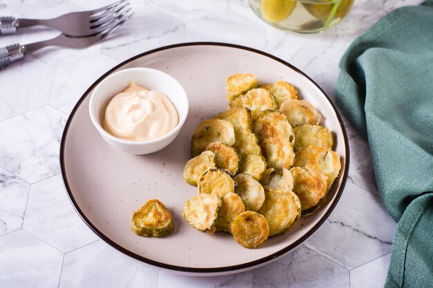 Apéritif de cornichons frits et sauce dans un bol sur une assiette Snack maison