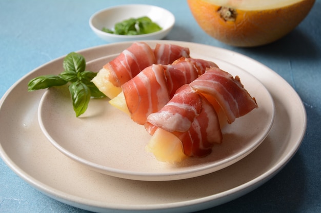 Apéritif d'été avec melon sucré et jambon sur fond bleu