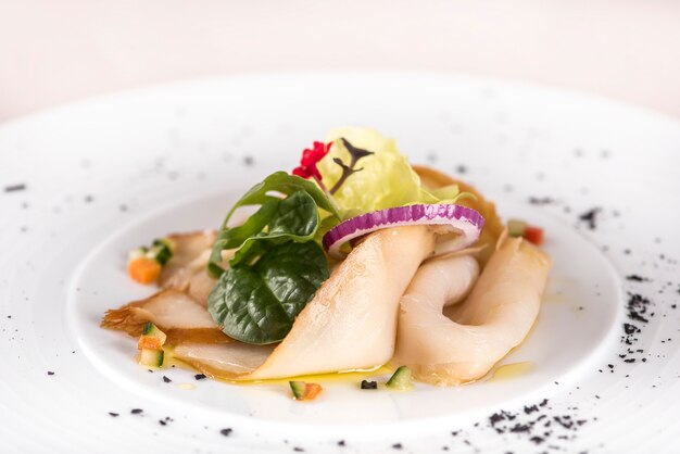 Apéritif frais avec poisson blanc fumé, rucola, pousses d’épinards et salade verte, avec fleurs rouges