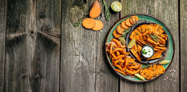 Apéritif de frites de patates douces avec citron vert et herbes sur plaque. Format de bannière longue. vue de dessus. Concept de cuisine végétarienne