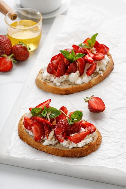 Apéritif avec fromage à la crème ricotta miel fraise menthe sur tableau blanc Toast snack