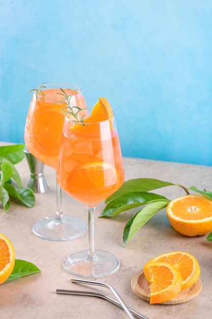 Apéritif italien classique aperol spritz cocktail en deux verres avec glace orange sur fond bleu sur podium en marbre