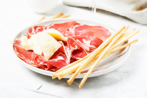 Apéritif italien traditionnel avec du fromage, du jambon et des bâtonnets de pain, mise au point sélective