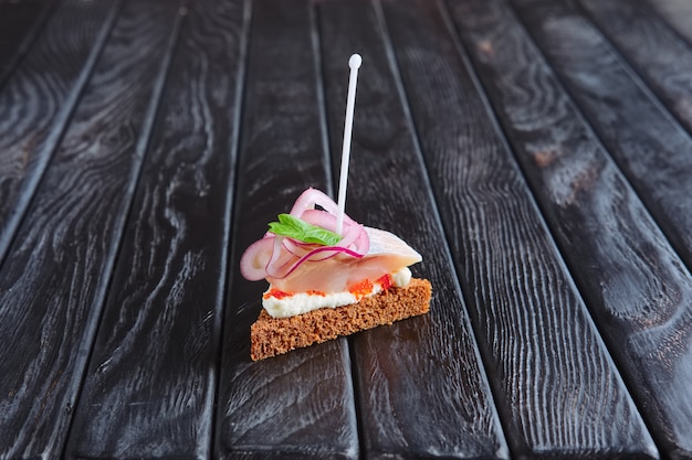 Photo apéritif à la réception. petit sandwich avec des harengs, du fromage et de l'oignon sur une brochette