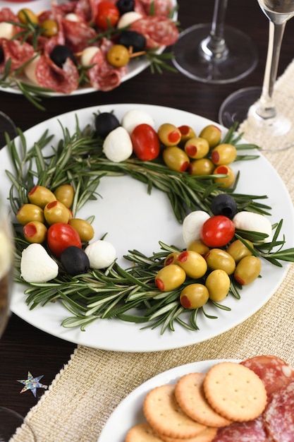 Un apéritif de romarin farci aux olives avec mini mozzarella et tomates cerises. Fabriqué sous la forme d'une couronne de Noël.