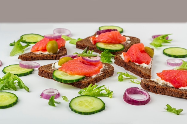 Apéritif, sandwich ouvert au saumon, oignon et concombre sur fond blanc. Cuisine traditionnelle italienne ou scandinave. Concept d'une bonne nutrition et d'une alimentation saine. Fermer