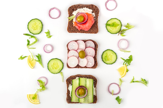 Apéritif, sandwich ouvert avec différentes garnitures: saumon et légumes sur fond blanc. Cuisine traditionnelle italienne ou scandinave. Alimentation équilibrée