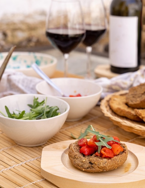 Apéritif typiquement italien du sud de l'été Friselle avec huile de tomates cerises et rucola servi en plein air