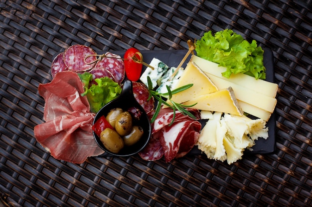 Photo apéritif viande et fromage avec olives marinées et feuilles de laitue.