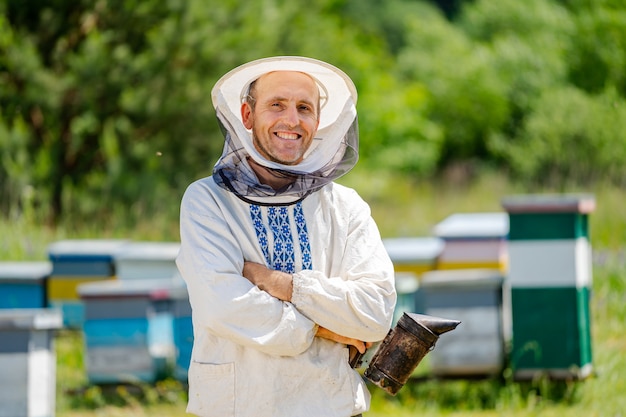 L'apiculteur se tient croisé près du rucher. Apiculture. Rucher.