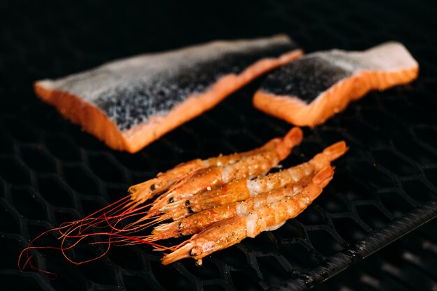 Appareil de cuisine professionnel. Fruits de mer frais. Gros plan du filet de saumon et des langoustines cuites dans un fumoir barbecue.