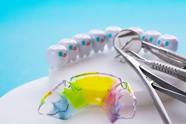 Appareil orthodontique de retenue dentaire et outils dentaires sur fond bleu.