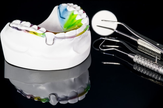 Appareil orthodontique de retenue dentaire et outils dentaires sur fond noir.