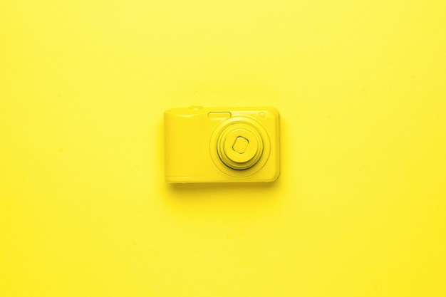 Un appareil photo jaune vif sur un fond jaune vif. Image monochrome de matériel photographique. Mise à plat.