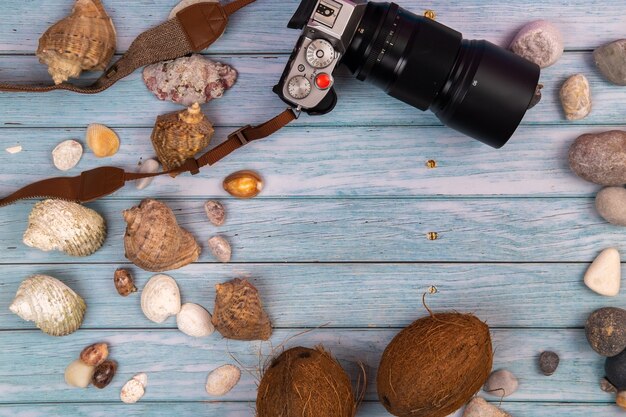 Appareil photo, noix de coco et coquillages sur un fond en bois bleu. Thème marin