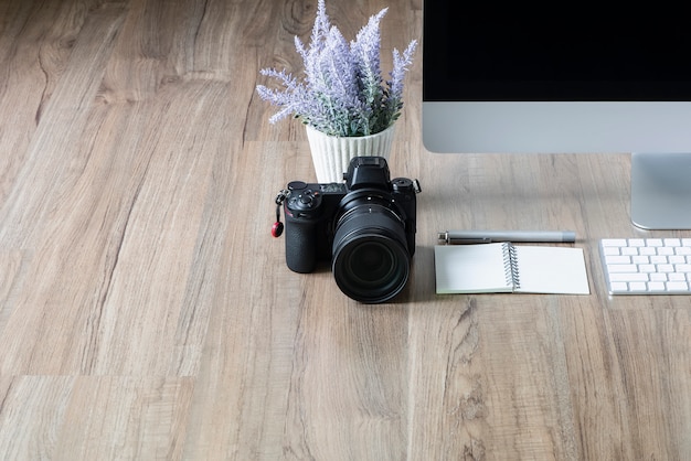 Appareil photo numérique, ordinateur de bureau et plante d&#39;intérieur sur fond de table en bois