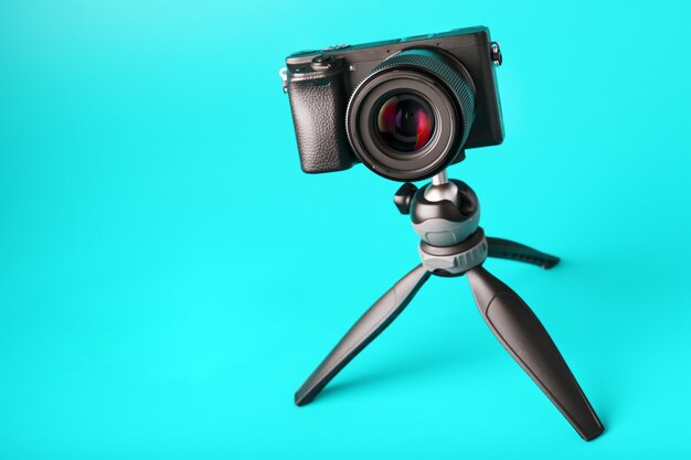 Appareil photo professionnel sur un trépied, sur fond bleu. Enregistrez des vidéos et des photos pour votre blog ou votre rapport.