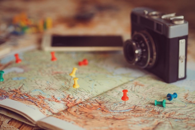 Un appareil photo et un téléphone portable avec des épingles colorées sur la carte
