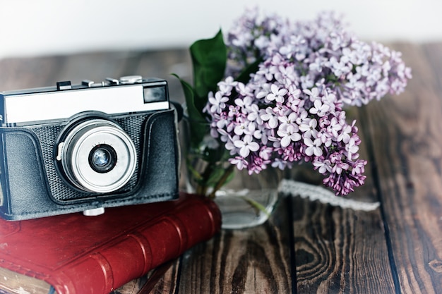 Appareil photo vintage et bouquet de fleurs de printemps lilas sur bac en bois