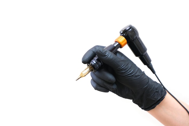 Appareil pour tatouer. outil de tatouage sur un fond blanc isolé est dans une main dans des gants noirs.