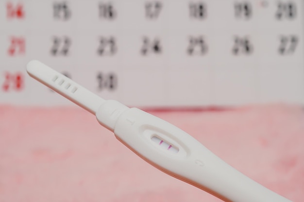 Appareil de test de grossesse pour déterminer une femme enceinte sur le calendrier Concept de santé et de médecine