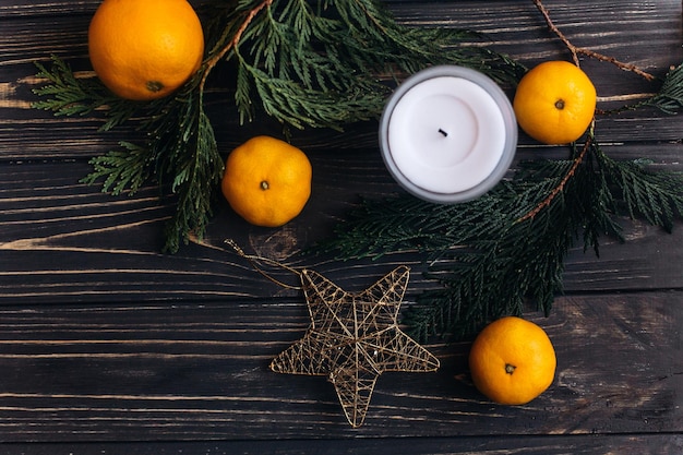 Appartement de noël élégant avec des branches vertes et des oranges et une étoile dorée sur fond en bois rustique noir salutation saisonnière et espace de concept publicitaire commercial pour textxA