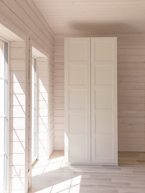 Appartements de style scandinave. Intérieur de chambre clair dans une maison en bois organique de couleur blanche. Meubles Ikea, armoire. Parquet, murs, plafond en bois. Armoire blanche. Fenêtres panoramiques.