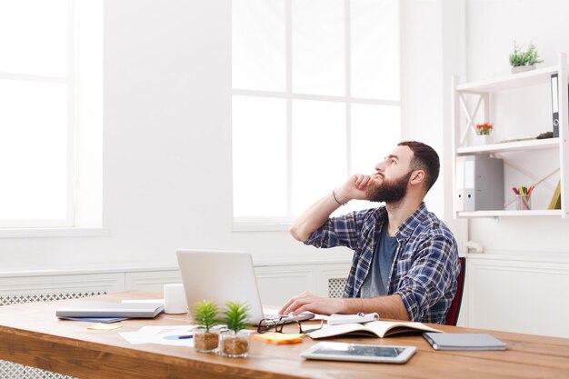 Appel de bureau, conversation d'affaires. Un jeune employé en tenue décontractée parle sur son téléphone portable dans un intérieur de lieu de travail moderne.