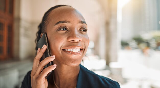 Photo appel téléphonique de femme noire heureuse et ville pour la communication en réseau ou la conversation visage d'une femme africaine souriant et parlant sur un smartphone pour une discussion d'affaires ou des conseils dans une ville urbaine