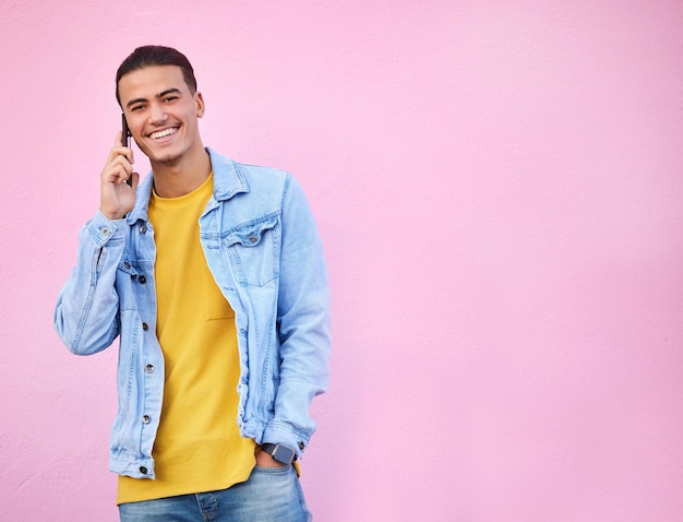 Appel téléphonique heureux et portrait d'un homme dans un studio avec une tenue décontractée à la mode et élégante Sourire heureux et modèle masculin sur une conversation mobile avec un téléphone portable par un fond rose avec un espace de maquette