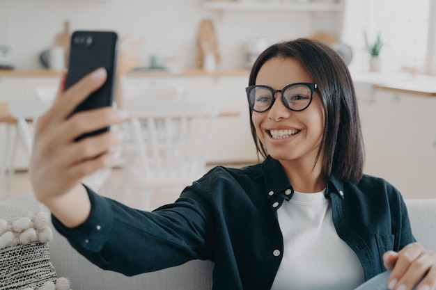 Appel téléphonique vidéo Une femme métisse heureuse se détend et discute sur un smartphone